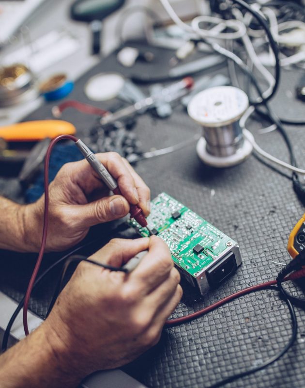 Repairman Checking Voltage With Digital Multimeter Engineer or technician repair electronic circuit board with soldering iron